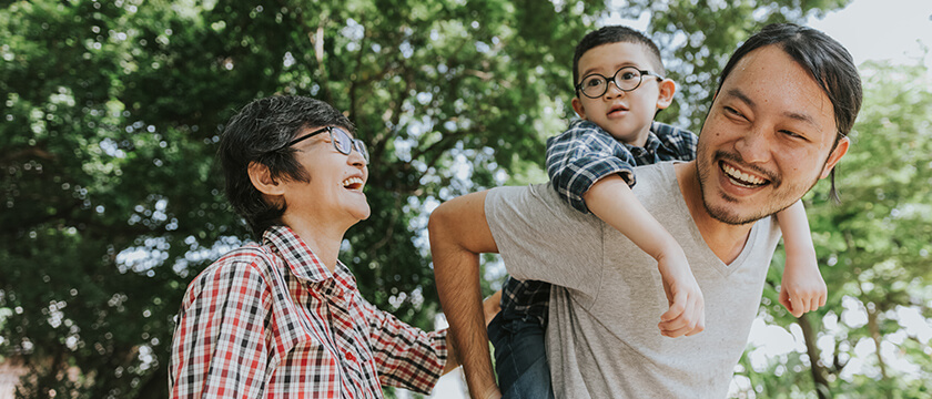 Asian family with a boy riding on dad's back, outside