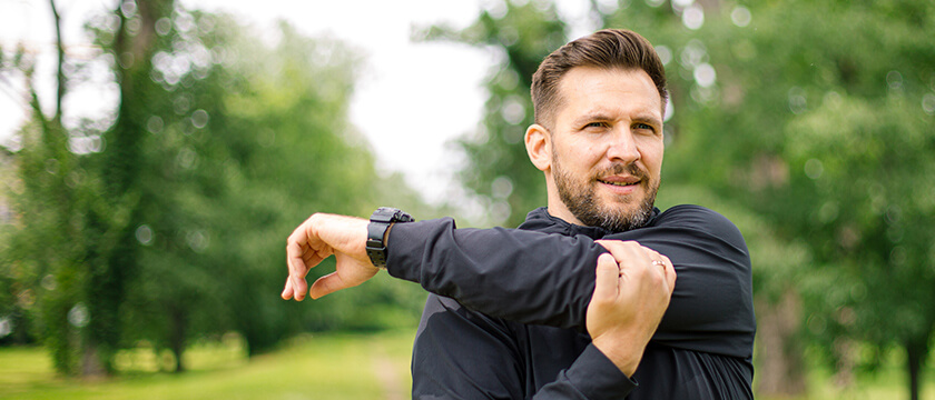 Athletic Man Stretching His Shoulder Outside