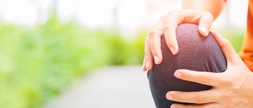 Woman Grasping Her Knee Outside, Close Up