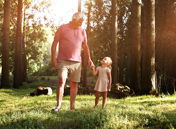 Mature man looking at his cute granddaughter in the forest