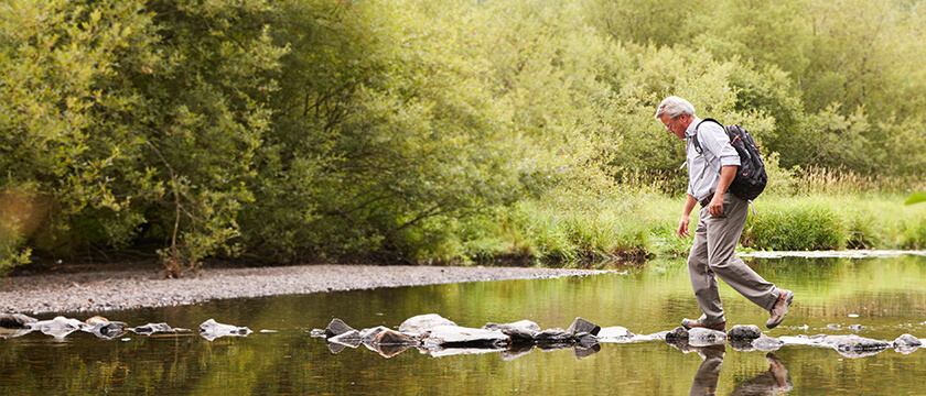 Man Crossing a Creek with a Backpack On