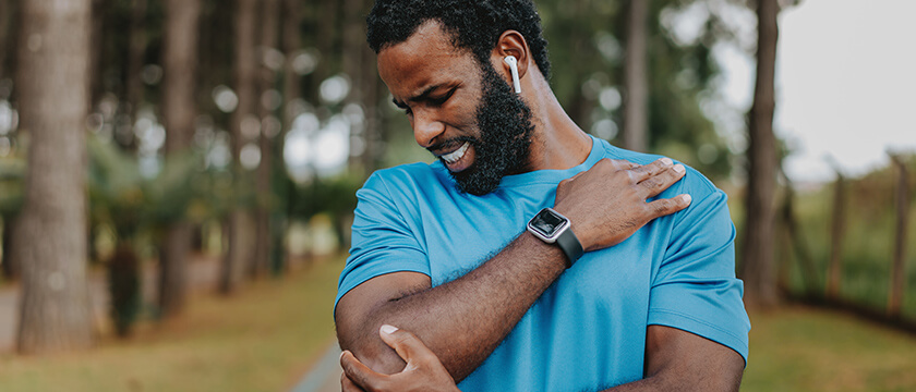 Black Man Feeling His Elbow for Pain, Grimacing