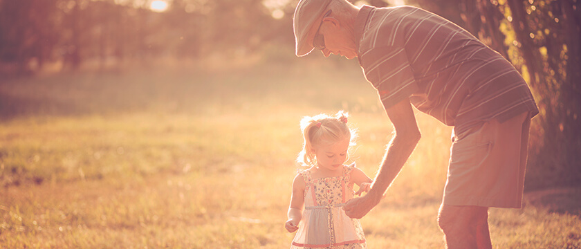 Man Being Handed Something from his Toddler Grandaughter Outside