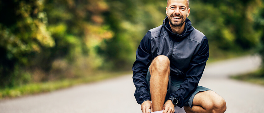 Man Stopping to Adjust Show on Wooded Road