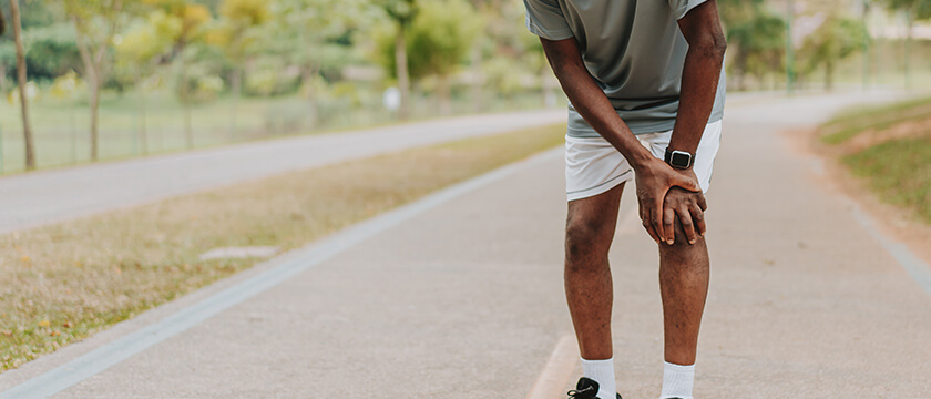 Man Stopped on a Road Grasping His Knee