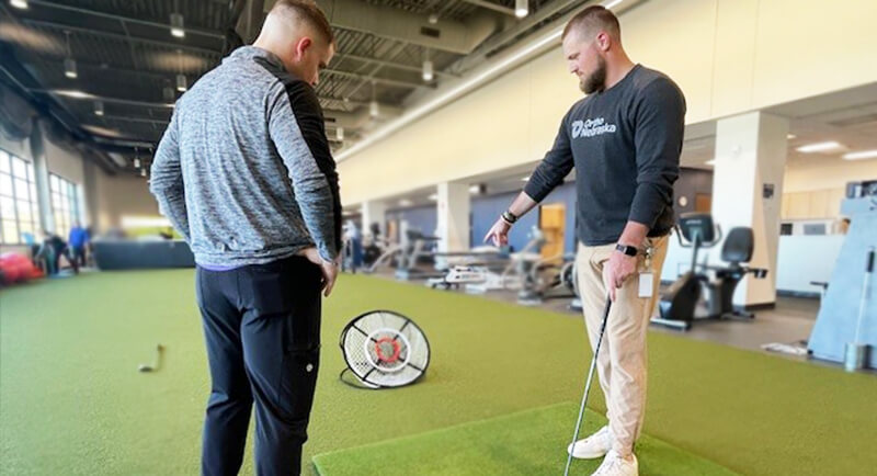 Therapist Nick Hunter helps a patient with their golf swing form