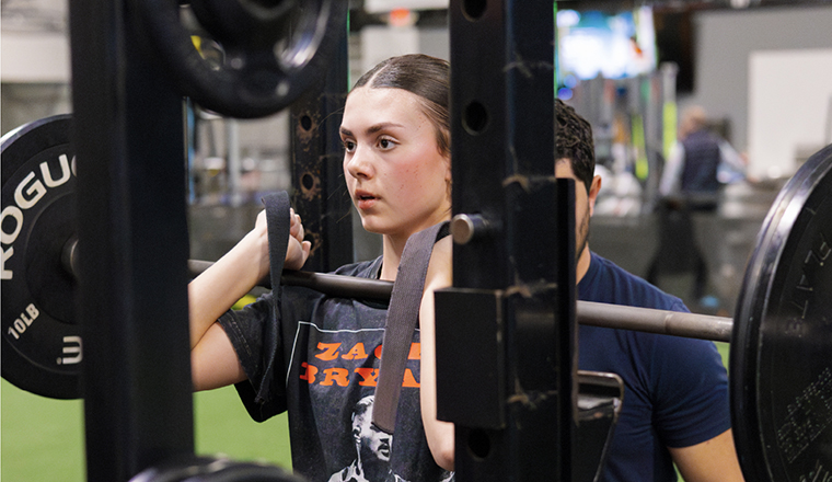 Woman lifting weights with a spotter