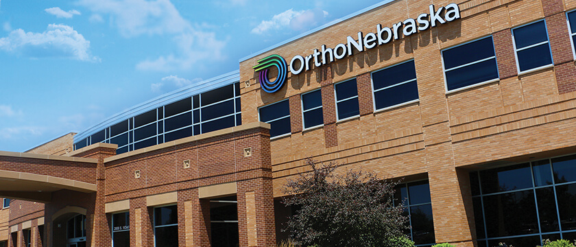 Tan, Brick Building with Overhang and OrthoNebraska Logo Facing West
