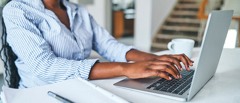 Woman Typing on a Laptop with Coffee