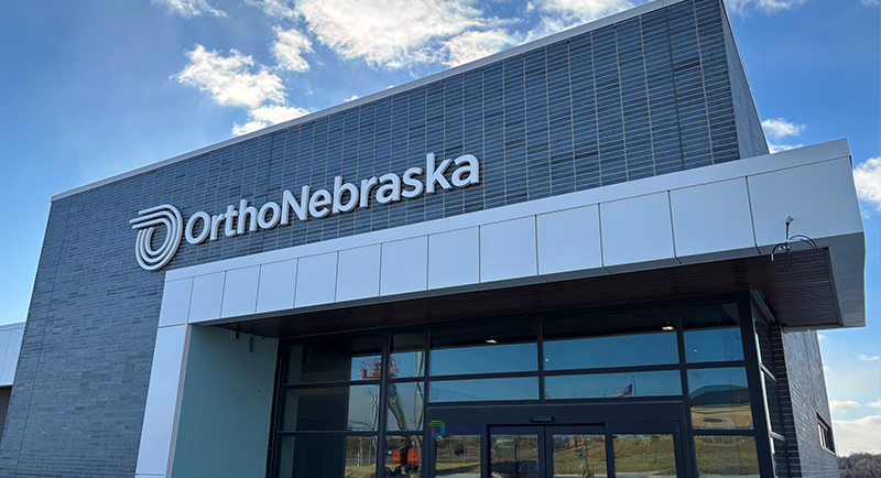 Gray building with OrthoNebraska written in white and white awning.