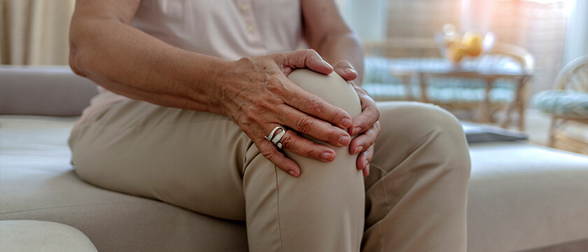 Woman Holding Her Right Knee on a Bed