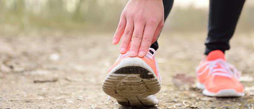 Woman Stretching Her Calf by Hand on Toe in Coral Shoes