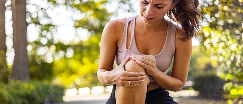 Young Woman Grasping Her Knee with a Concerned Look