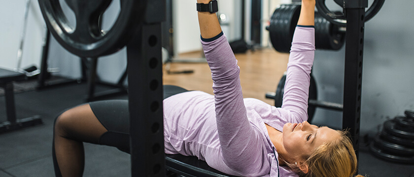 Woman Benchpressing Weights in Gym