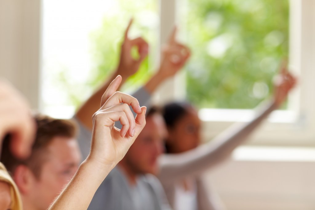 Many raising fingers in a class