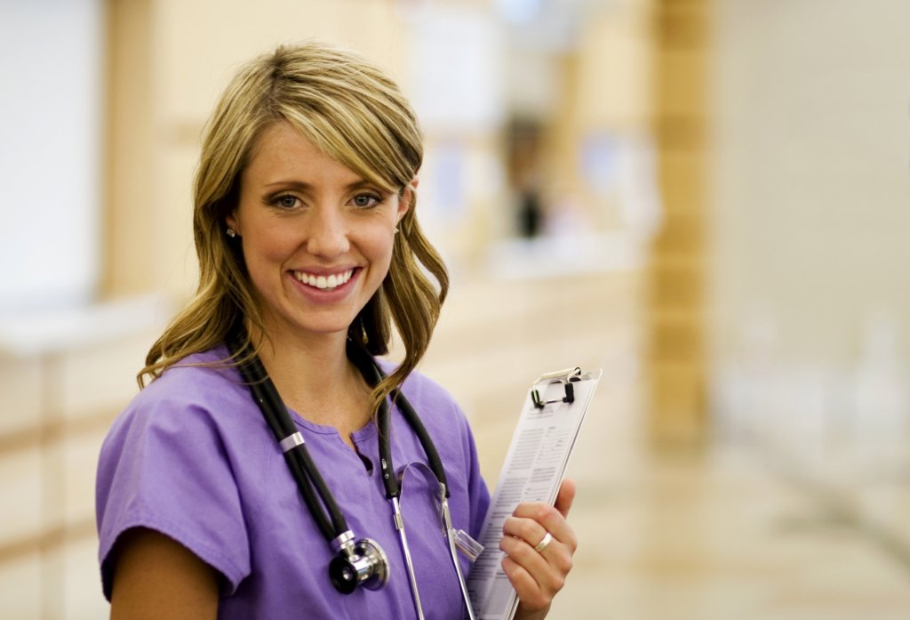smiling nurse wearing purple scrubs
