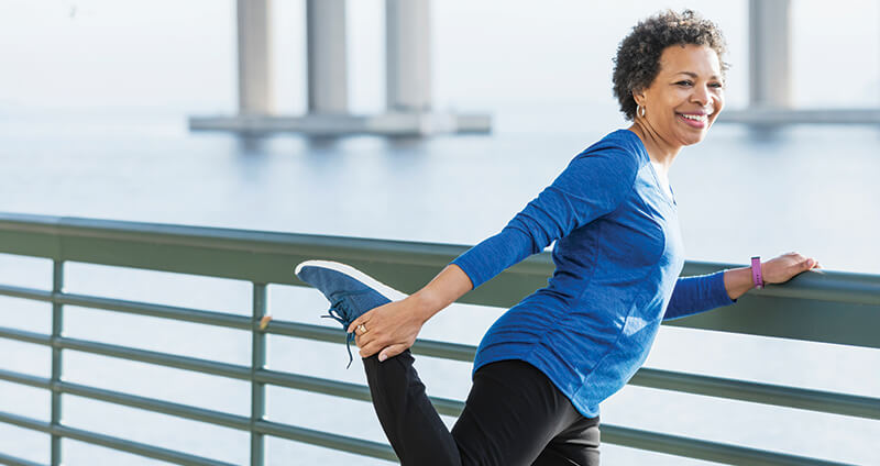 Woman Stretching Quad Leaning Against a Railing